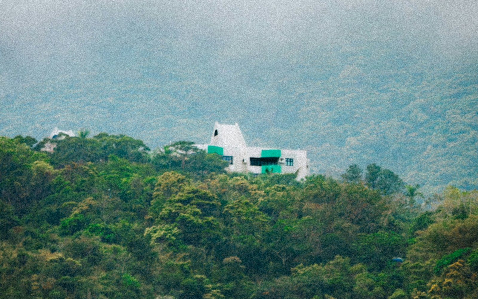 A white house on a green hillside under mist
