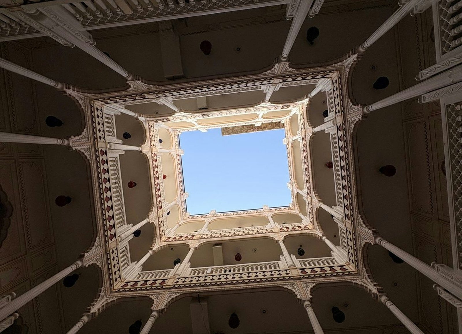 Looking up from a courtyard at balconies and a square of sky